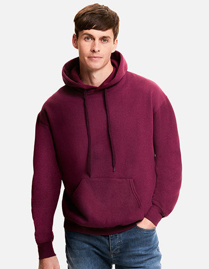 Mand iført en bordeaux hættetrøje fra Fruit of the Loom med hænderne i lommerne, stående i en afslappet position mod en hvid baggrund. Han har også blå jeans på.